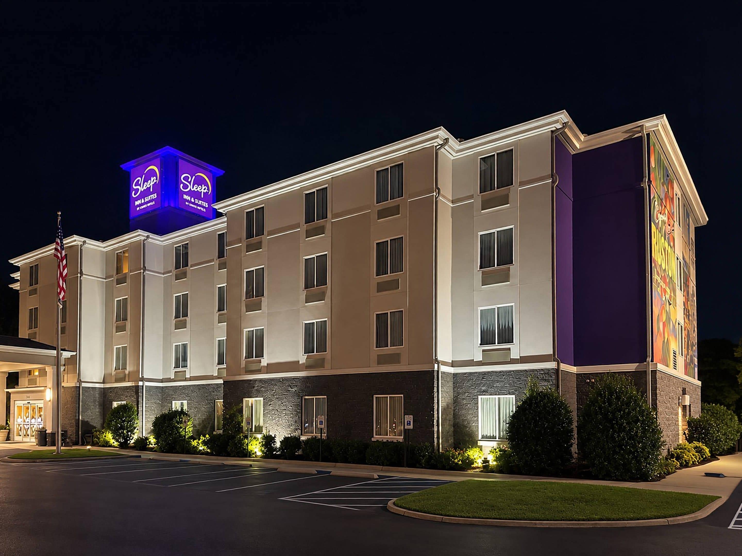 A multi-story hotel with a prominent neon sign, a parking lot, and a landscaped entrance area.
