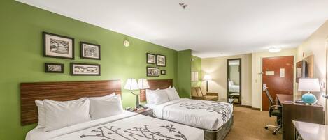 Quarto de hotel com duas camas, uma escrivaninha, uma cadeira e um espelho.