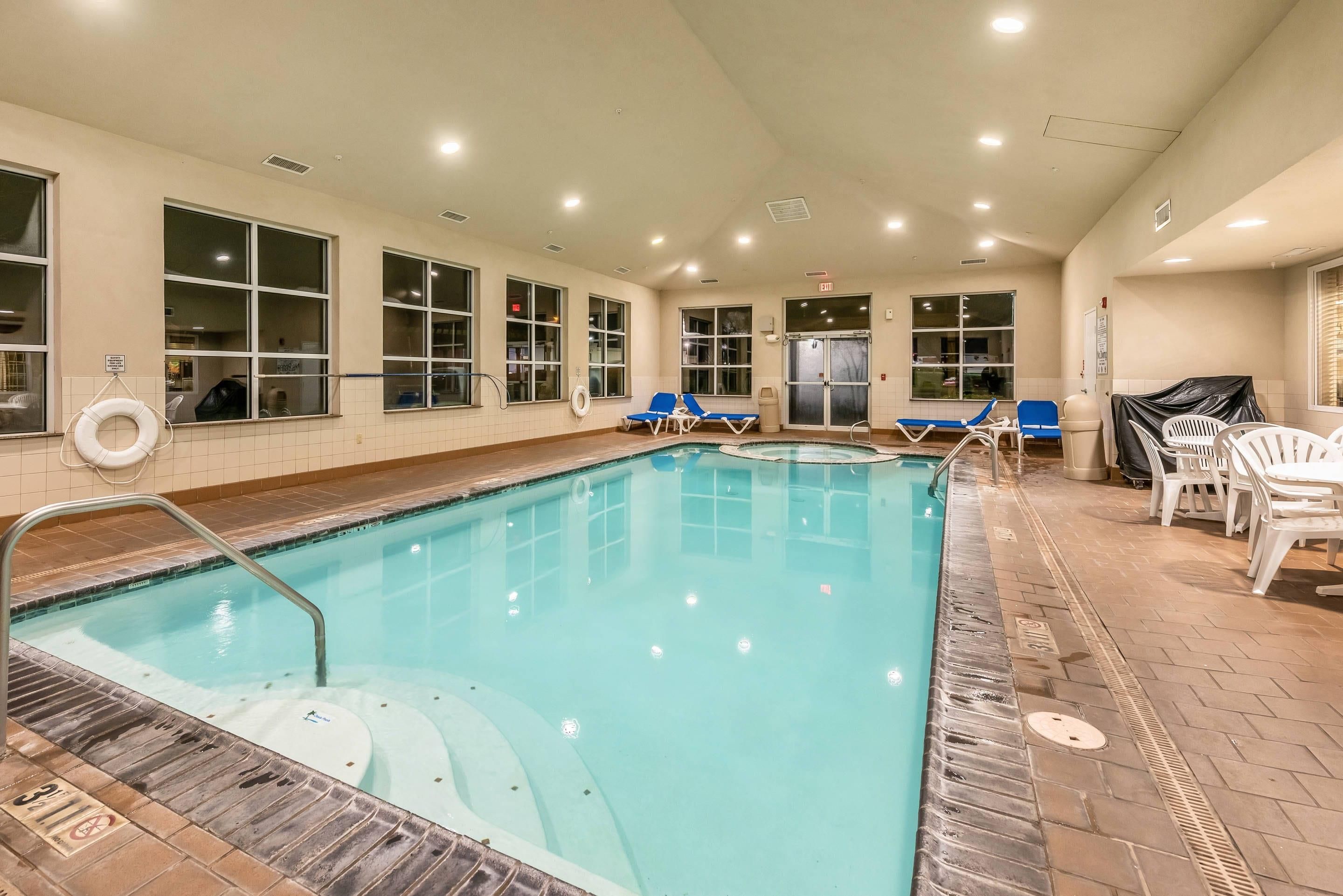 An indoor swimming pool with clear water, a lifeguard chair, and lounge chairs.