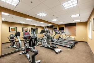 Un gimnasio con cintas de correr, elípticas y bicicletas estáticas.