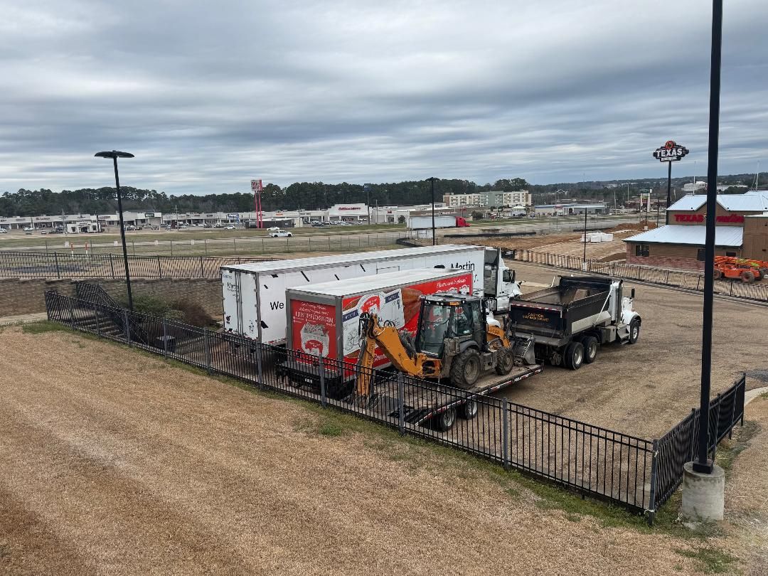 A large industrial area with a fenced enclosure, a white truck, and a yellow construction vehicle.