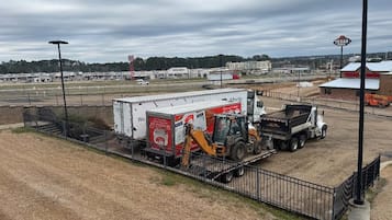 A large industrial area with a fenced enclosure, a white truck, and a yellow construction vehicle.