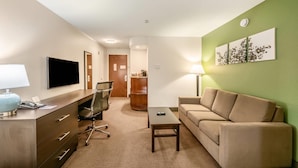 Habitación de hotel con escritorio, silla, sofá y televisión.