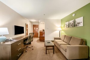 Habitación de hotel con escritorio, silla, sofá y televisión.