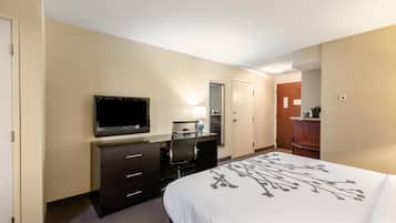 Une chambre d’hôtel comprenant un lit, un bureau avec une télévision, une chaise, une lampe de bureau et un miroir.