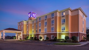 Un hotel de varios pisos con un cartel llamativo de 'Sleep Inn & Suites' y una bandera estadounidense.