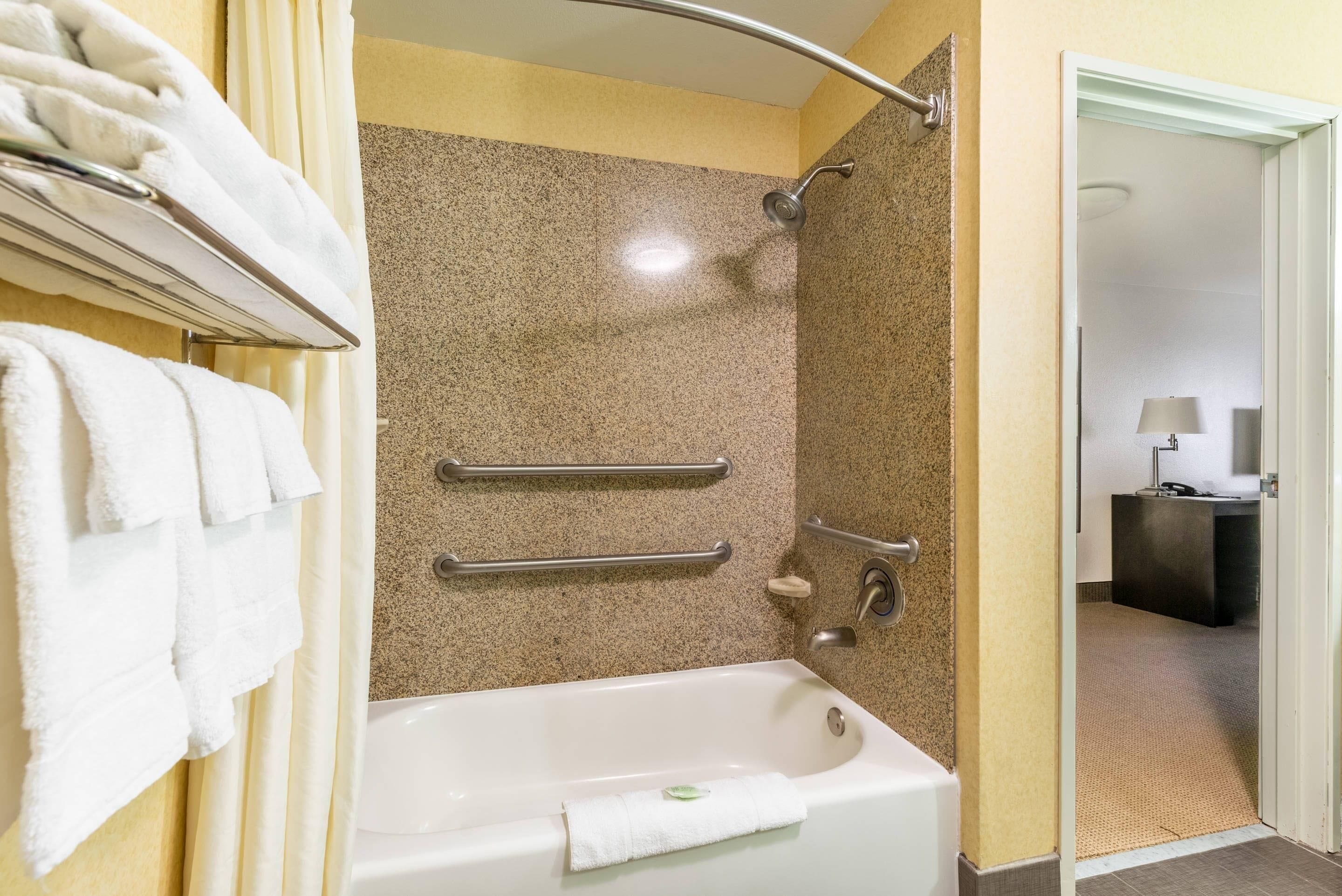 Une salle de bain équipée d’une baignoire, d’une douche et d’un porte-serviettes avec plusieurs serviettes.