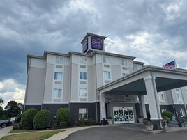 Un hotel Sleep Inn & Suites con entrada cubierta, estacionamiento y una bandera.