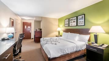 A hotel room with a bed, desk, chair, and two bedside lamps.