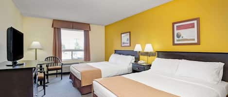 A hotel room with two beds, a desk with a TV, a chair, and a window with curtains.