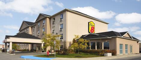 A hotel with a Super 8 sign, multiple floors, and a covered parking area.