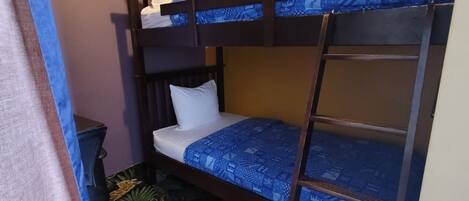 Une chambre avec un lit superposé, une couvre-lit à motifs bleus, un tapis à thème zèbre et une petite table de chevet.