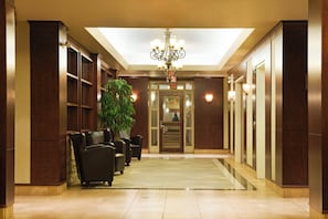 Un hall d'hôtel avec un lustre, un espace salon et un comptoir d'accueil.