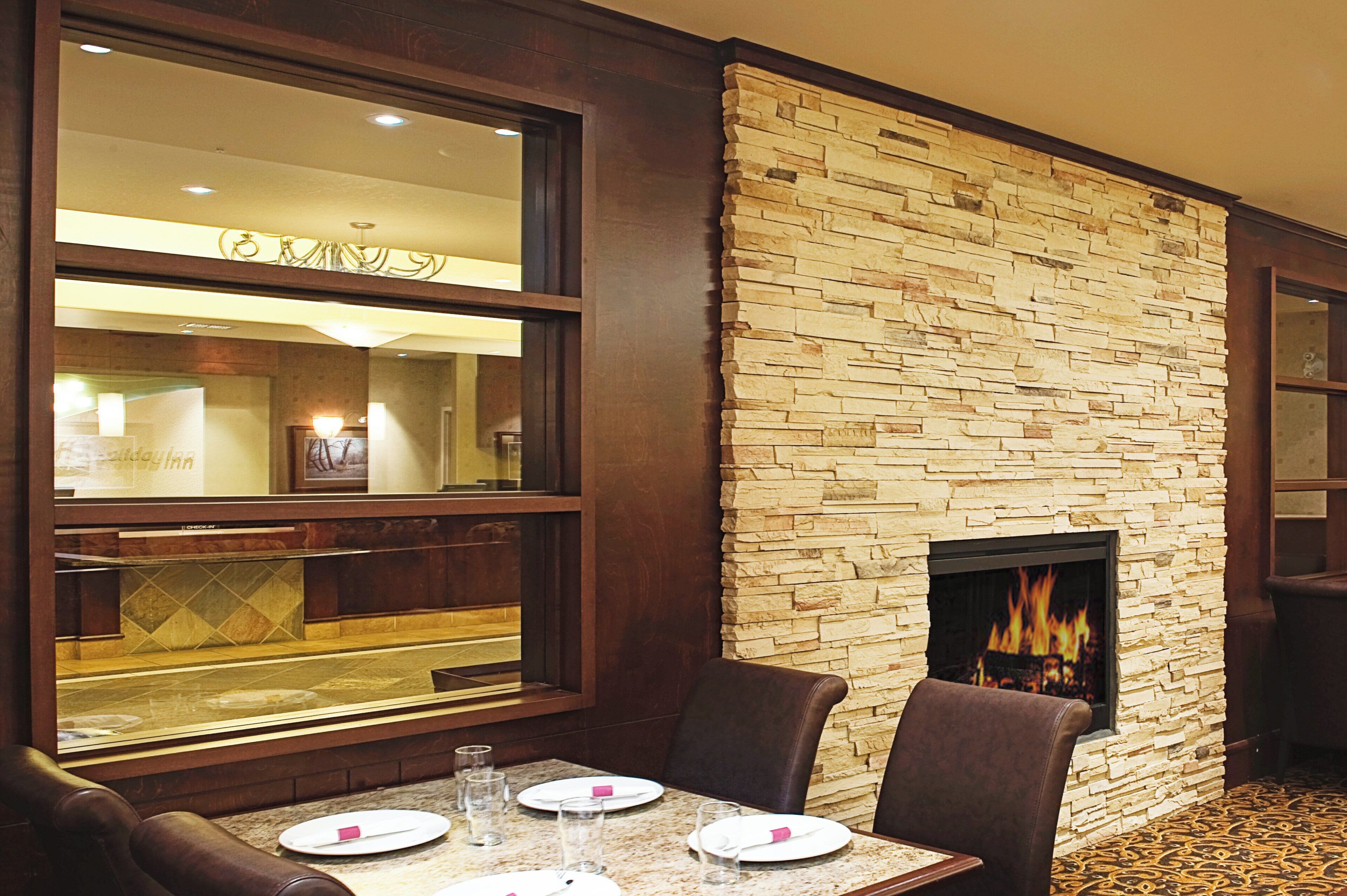 A dining area with a stone wall and a fireplace. There are tables and chairs set for dining.