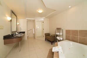 A modern bathroom with a large bathtub, a separate shower area, and a seating area with towels. - Holiday Inn Hotel & Suites Lloydminster by IHG (Lloydminster)