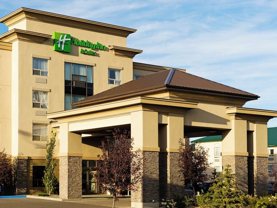 A Holiday Inn & Suites building with a flat facade, multiple windows, and a covered entrance area.