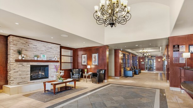 A spacious lobby with a stone fireplace, leather seating, and a chandelier. - Holiday Inn Hotel & Suites Lloydminster by IHG (Lloydminster)