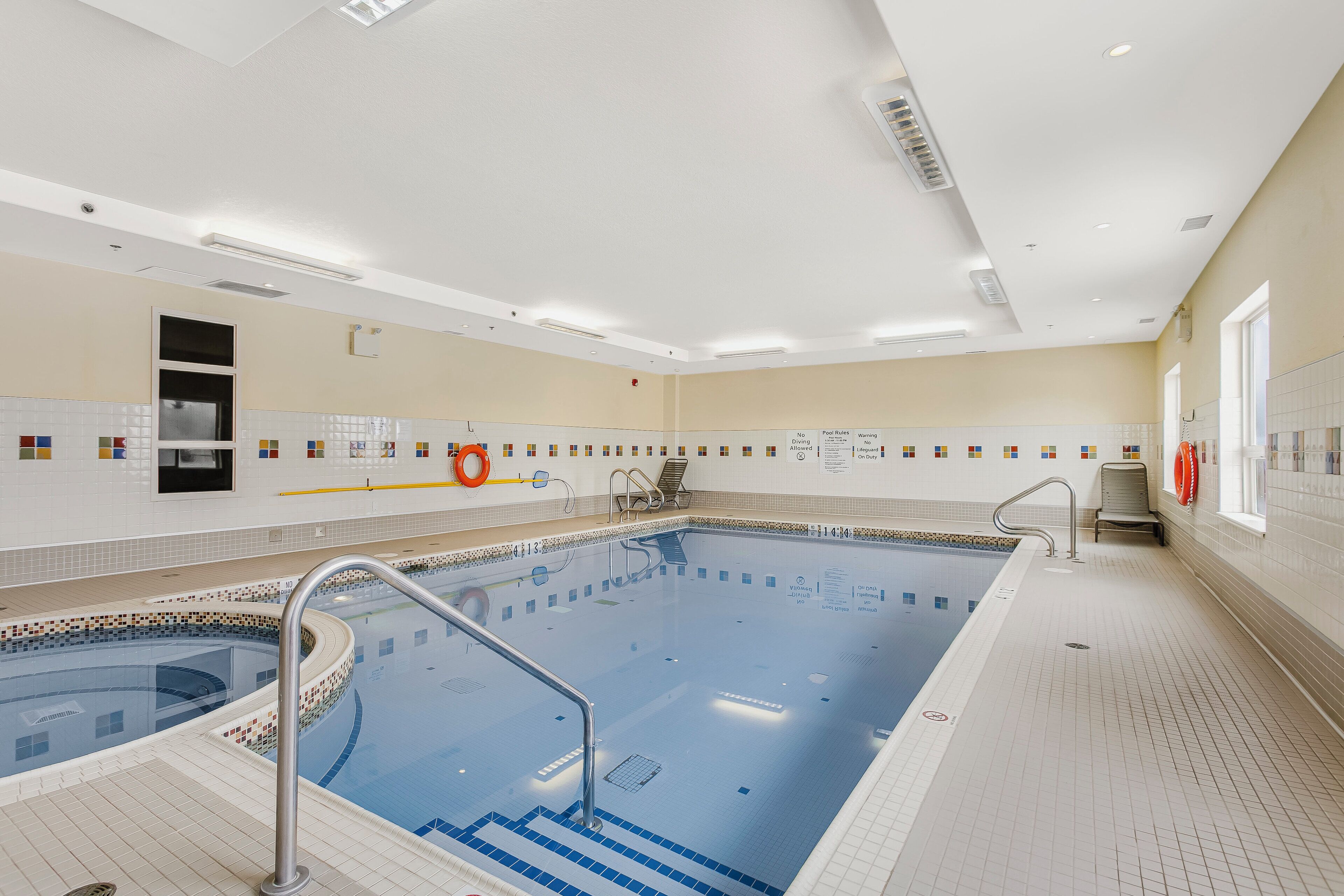 Una piscina con escalones de acceso, un flotador salvavidas y un ventanal con vistas a la piscina.
