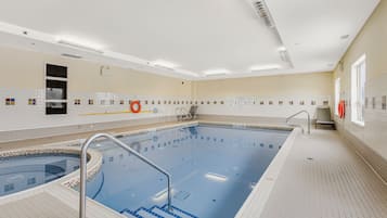 Una piscina con escalones de acceso, un flotador salvavidas y un ventanal con vistas a la piscina.