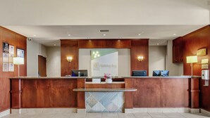 Un área de recepción con un mostrador de madera, un separador de vidrio y un cartel que dice 'Holiday Inn'.