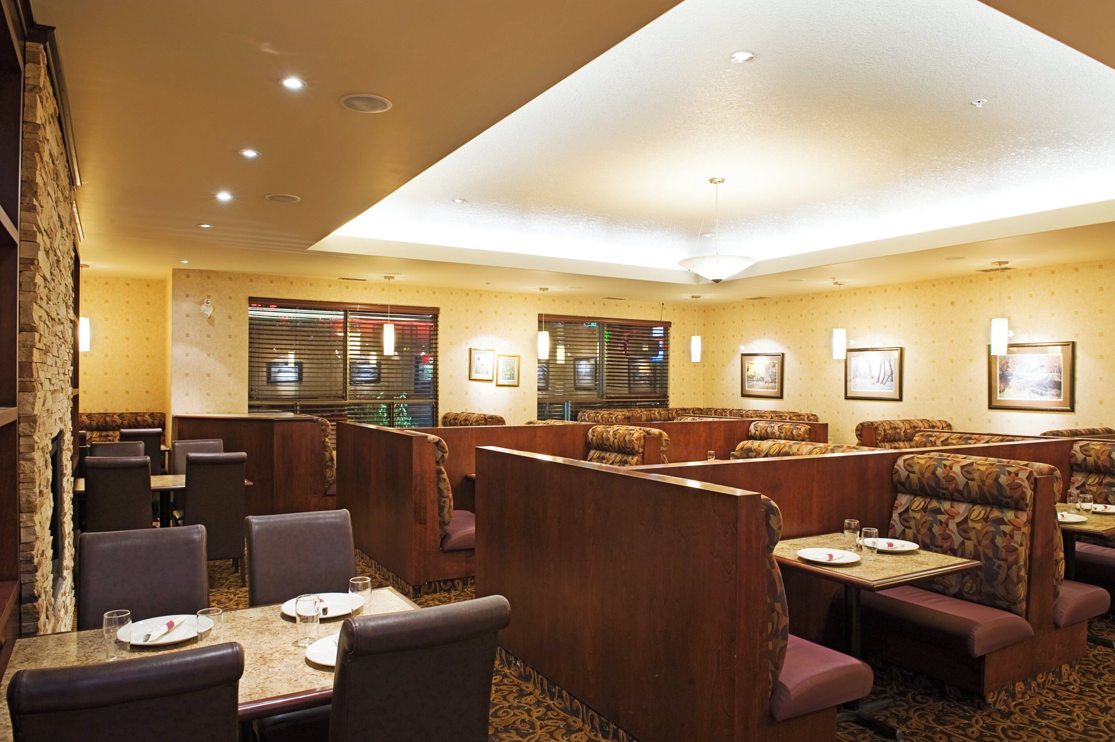 Un restaurante con asientos tipo cabina, mesas individuales y una pared de acento de piedra.