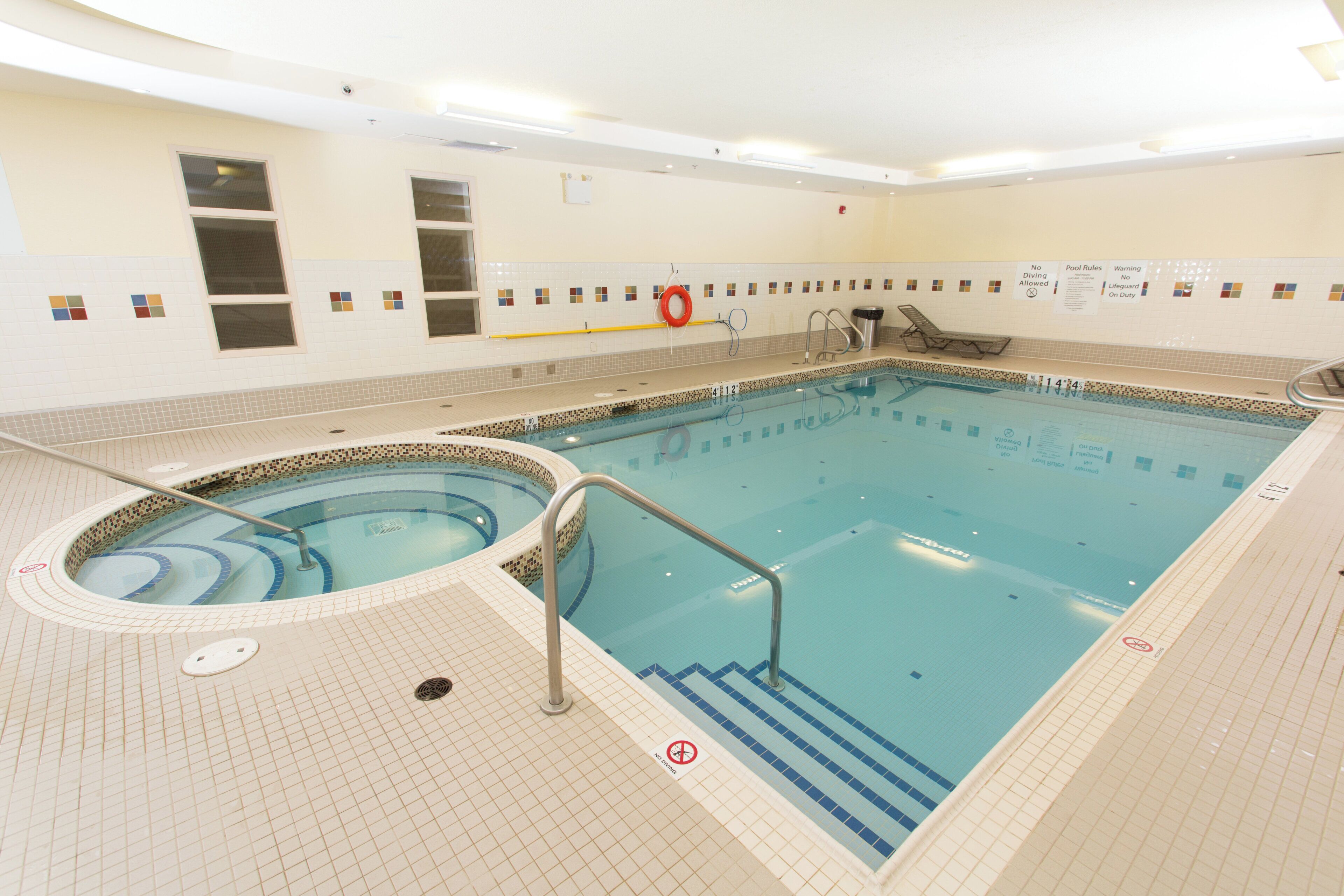 Una piscina con hidromasaje, paredes enlosadas y una silla de salvavidas.
