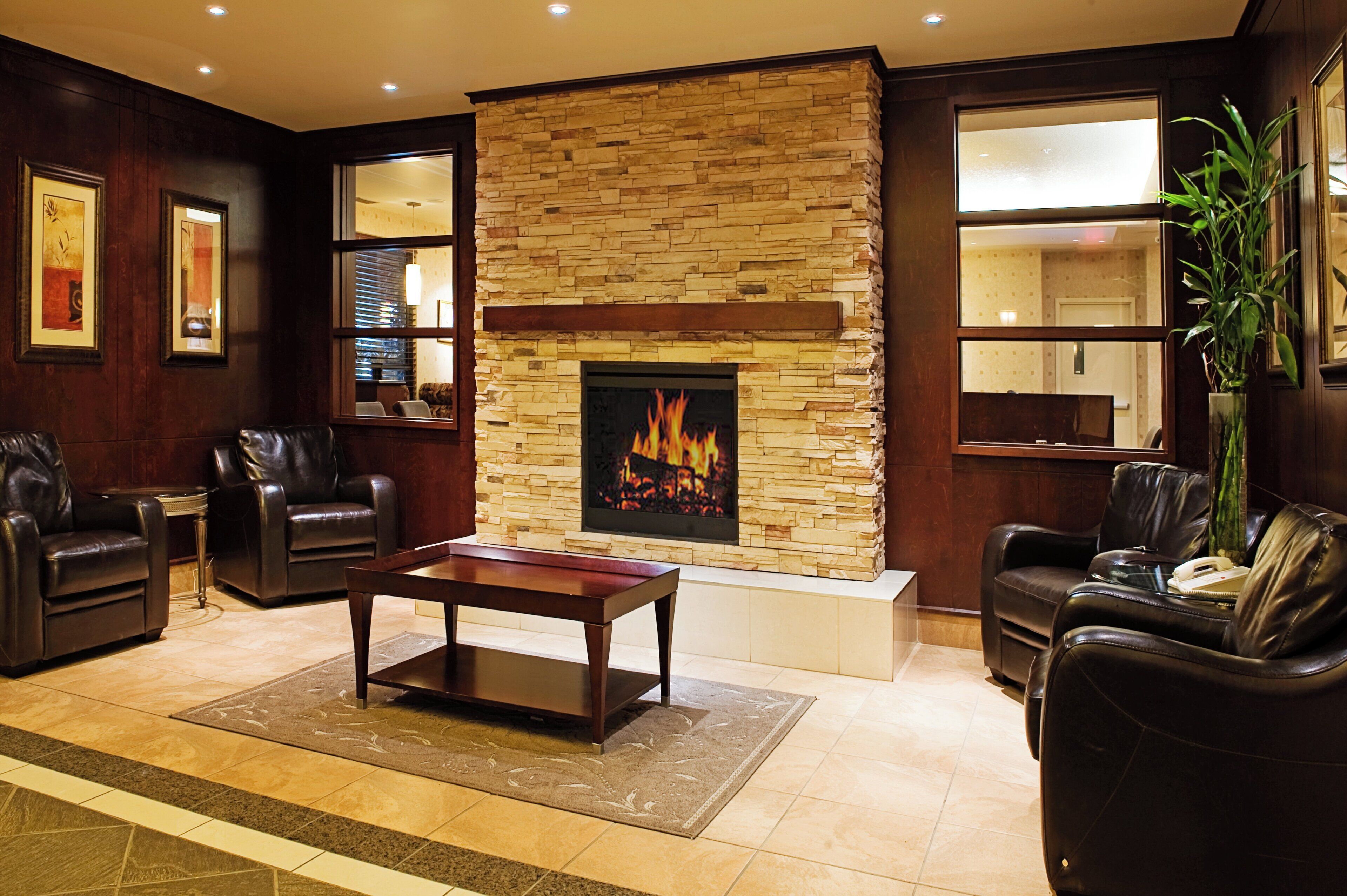 Una sala moderna con chimenea de piedra, sofás de cuero y una mesa de centro.