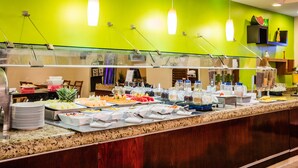 Un bufé con distintos alimentos y una pared verde al fondo.