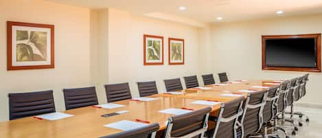 A conference room with a long table, black chairs, and framed pictures on the walls.