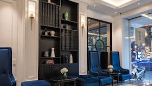A modern lobby with dark wood shelving, blue upholstered seating, and a patterned floor.