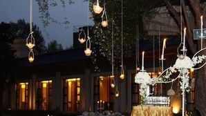Un espace événementiel en plein air, agrémenté de luminaires suspendus et d’une table recouverte d’une nappe dorée.