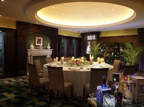A round dining table with chairs, a fireplace, and decorative plants. - Jin Jiang Nanjing Hotel (Nanjing)