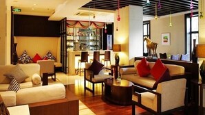 Un hall d’hôtel moderne doté d’un bar, d’espaces aménagés pour s’asseoir et d’un plafond décoratif.