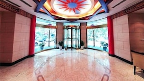 Un hall d’hôtel doté d’un plafond circulaire central, de portes en verre et d’un sol en marbre poli.