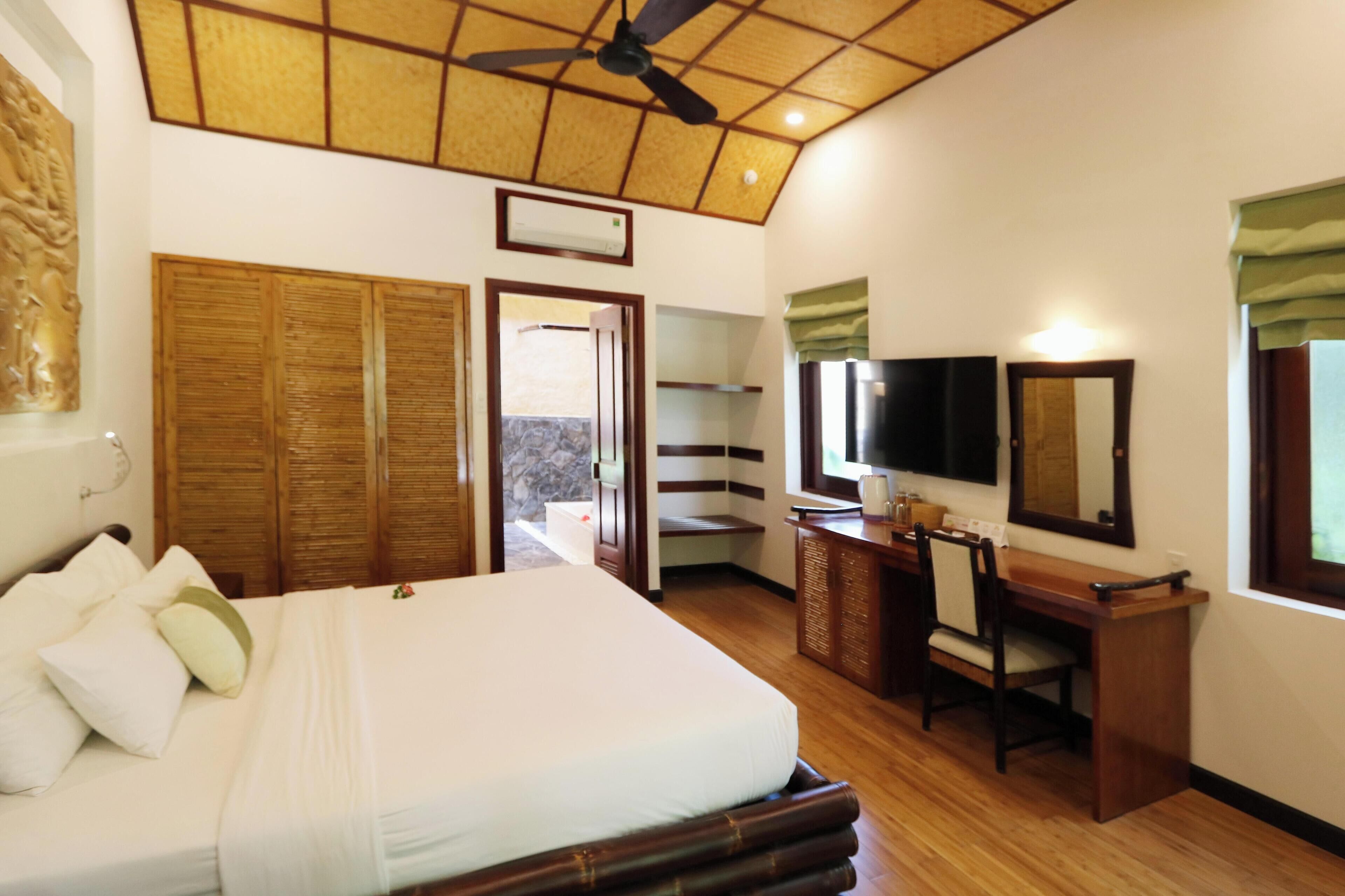 Un dormitorio con cama, escritorio, silla, televisor y espejo.