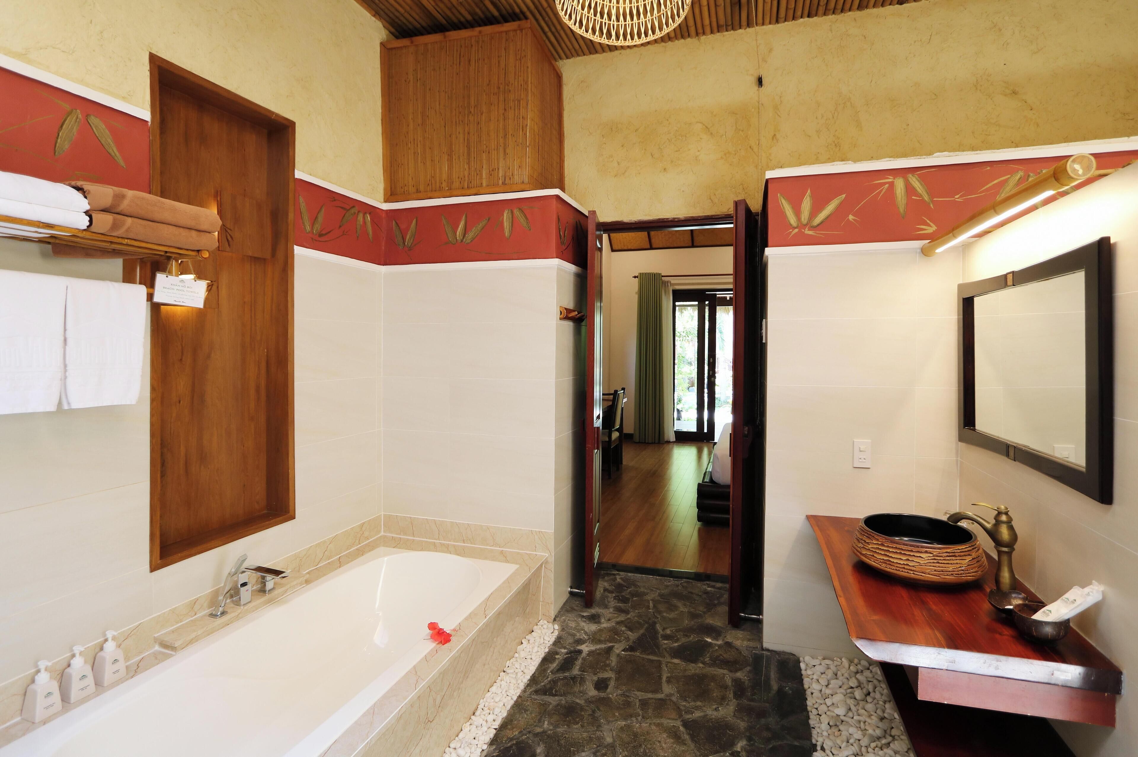 Un baño con bañera, tocador de madera y espejo.