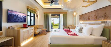 A hotel room with a large bed, a television, a desk with a computer, and a view of the outdoors.