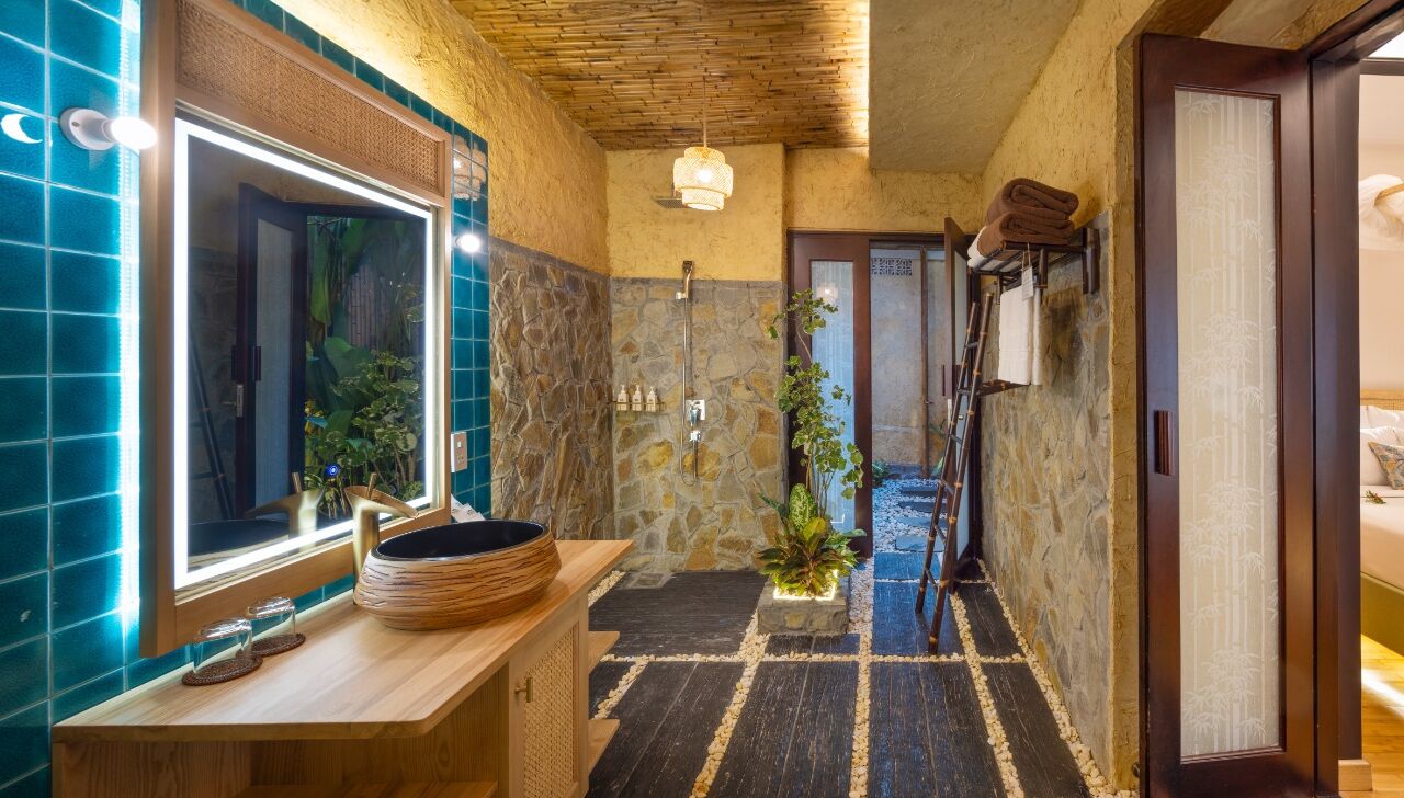 Une salle de bain avec un mur en pierre, un meuble-lavabo en bois, un grand miroir et un espace douche.