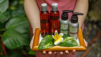 A person holding a tray with three bottles of liquid and a flower.