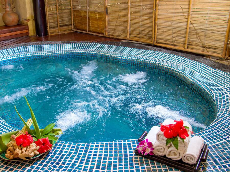 A hot tub with a tiled edge, surrounded by bamboo walls.