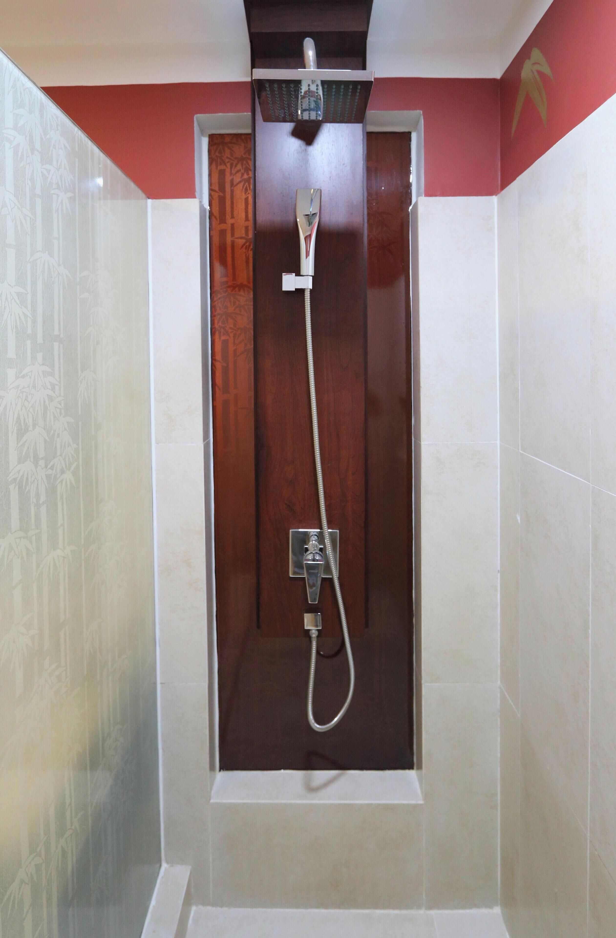 A shower with a wooden door, a handheld showerhead, and a wall-mounted faucet.