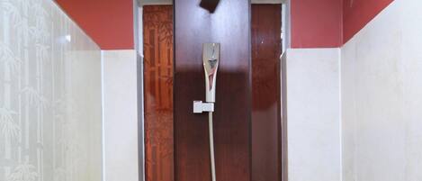 A shower with a wooden door, a handheld showerhead, and a wall-mounted faucet.