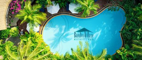 A resort with a swimming pool surrounded by lush greenery and palm trees.