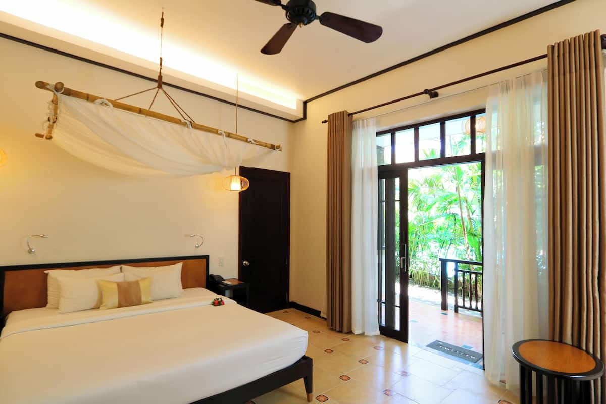 A hotel room with a bed, bedside table, and a ceiling fan.