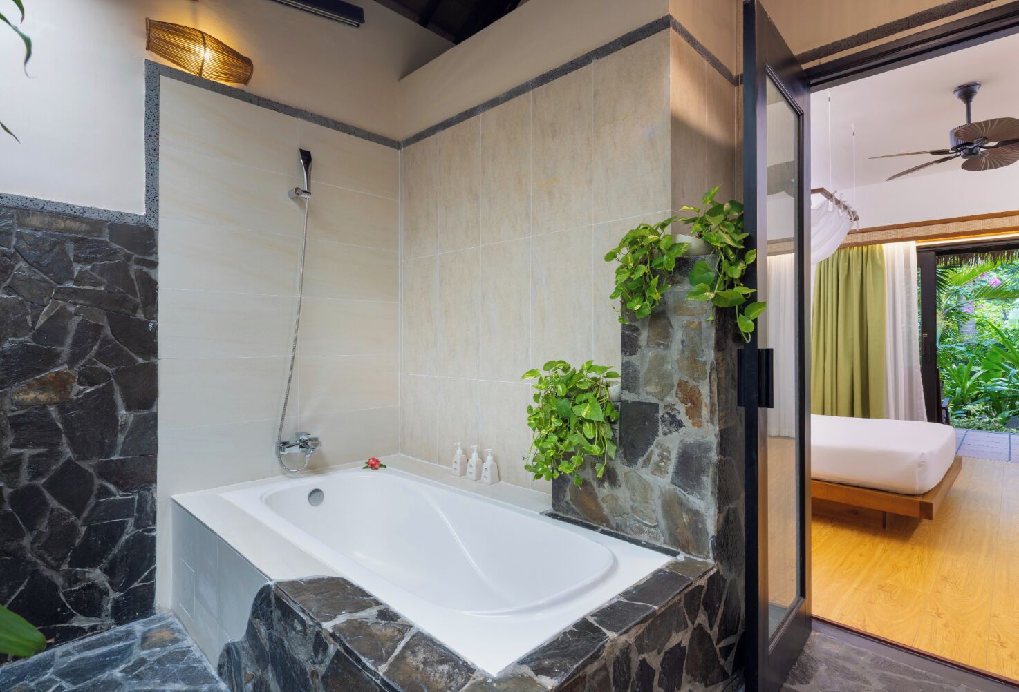 A modern bathroom with a stone accent wall, a bathtub, and a shower.