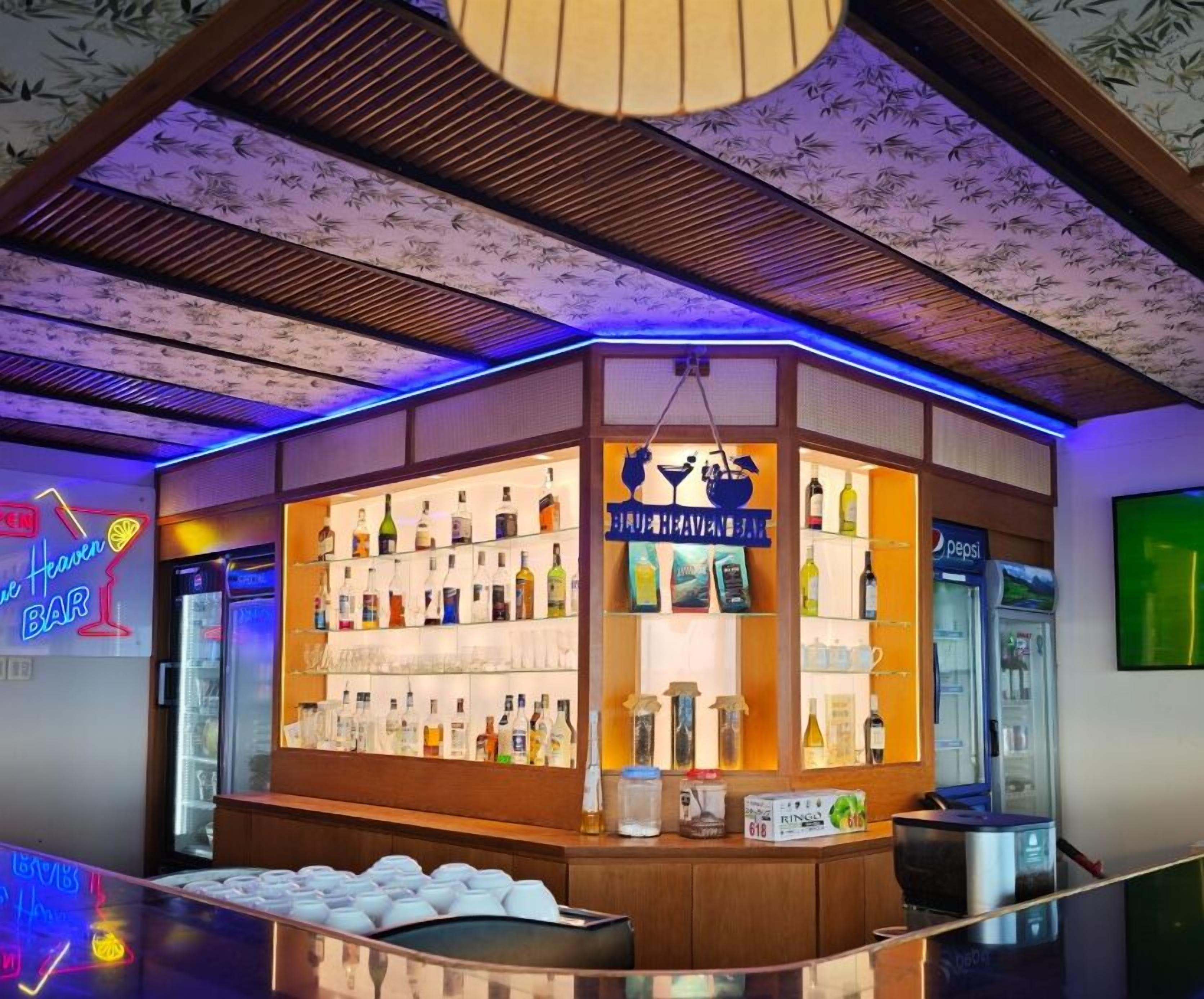 A bar area with shelves of bottles and a neon sign.