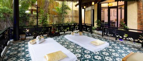 A spa area with two massage tables, a thatched roof, and a patterned floor.