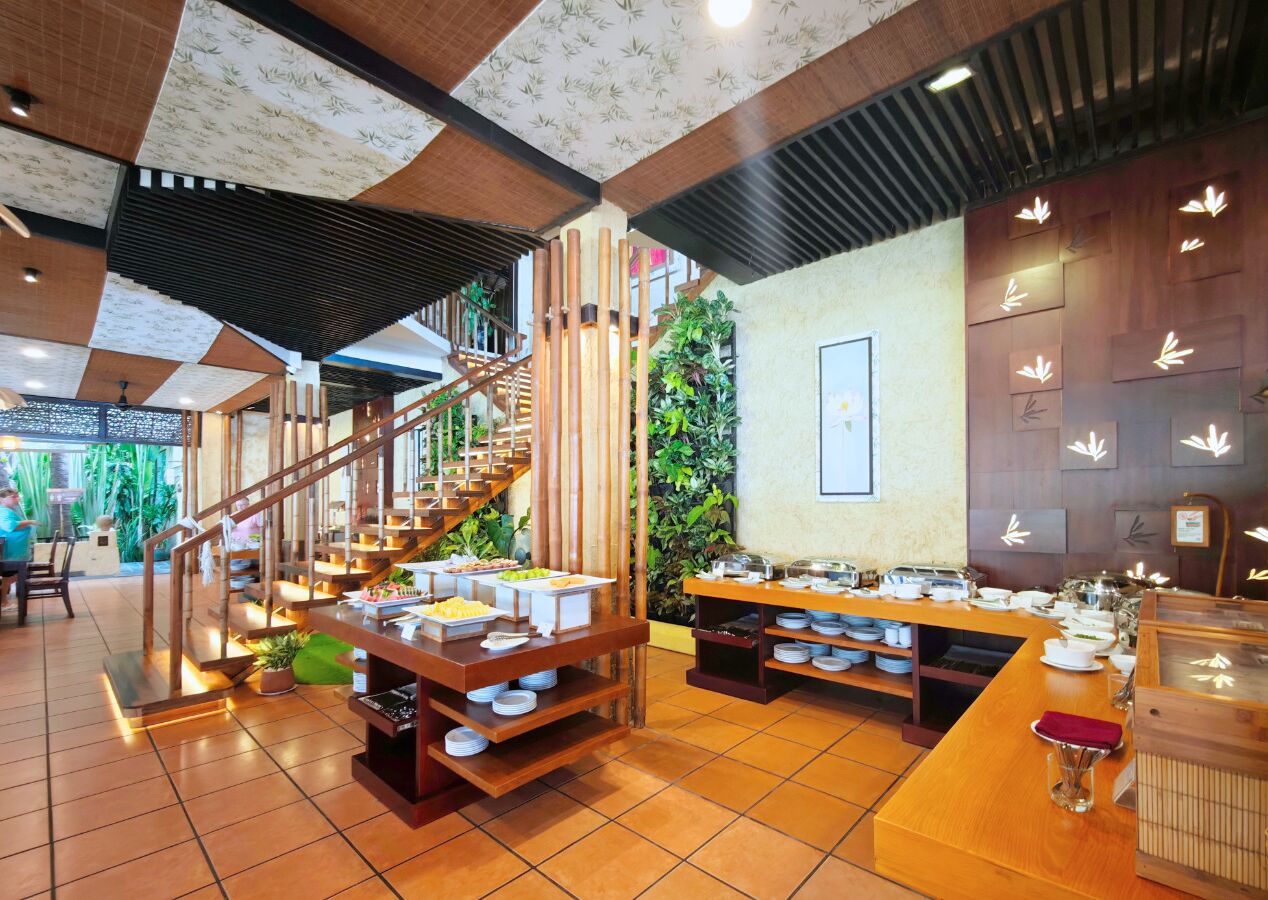 A buffet area with multiple serving stations, a staircase, and a wall decorated with bamboo leaves.