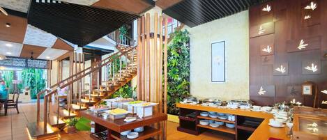 A buffet area with multiple serving stations, a staircase, and a wall decorated with bamboo leaves.