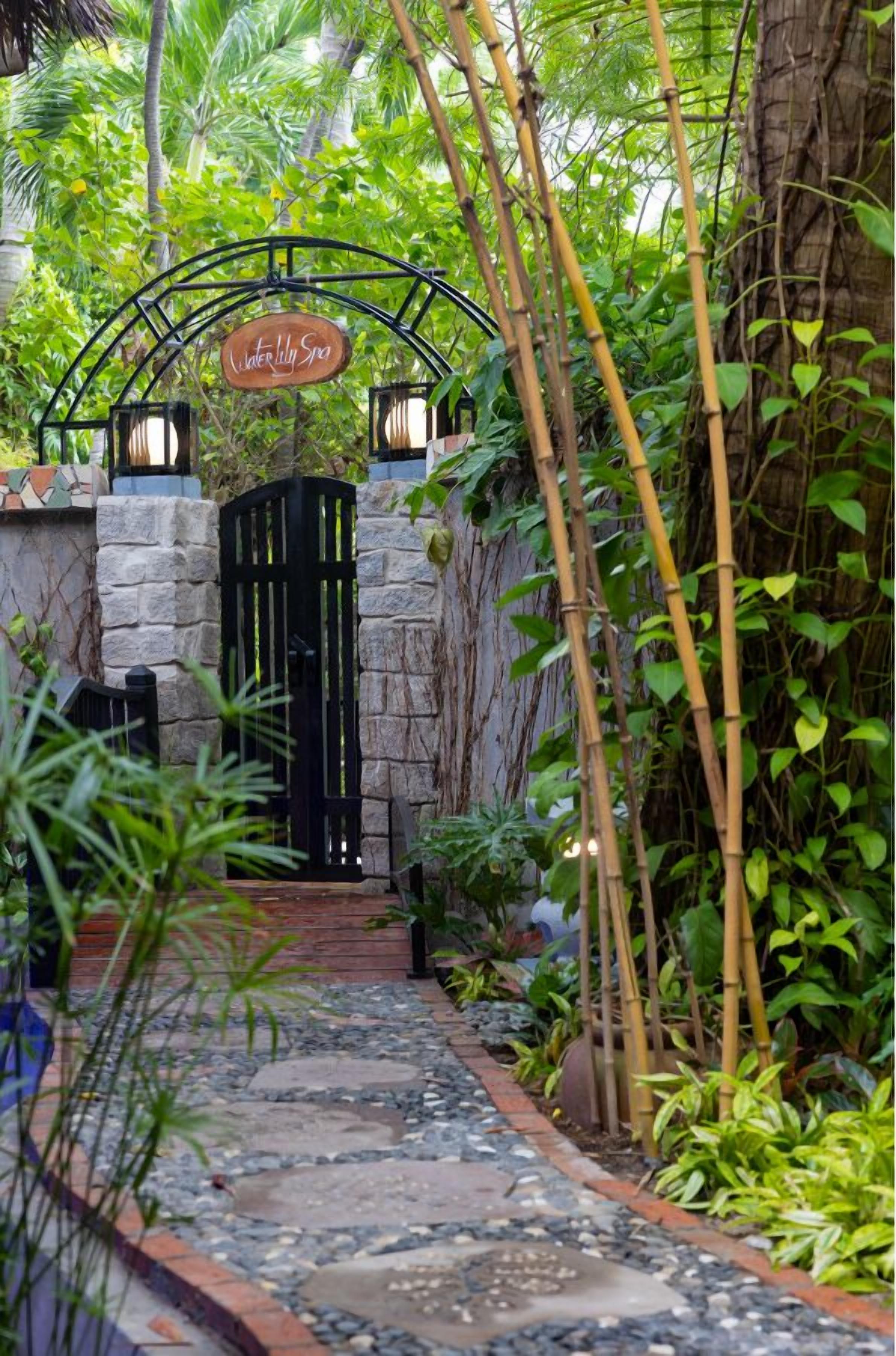 A pathway leading to a gate with a sign reading "Water Lily Spa".